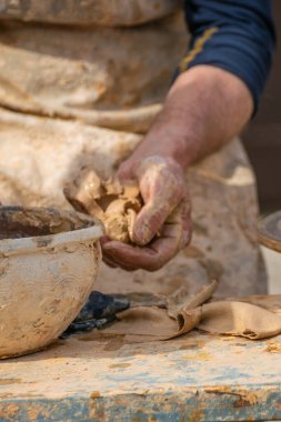 Bir çömlekçinin eli atölyesinde ıslak bir kil parçasını tutuyor.
