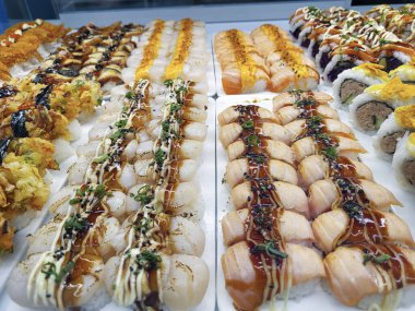 Yemek marketinin vitrininde suşi. Suşi, genellikle biraz şeker ve tuz ile birlikte deniz ürünleri ve sebzeler gibi çeşitli malzemelerle birlikte hazırlanmış bir Japon sirke pilavıdır..