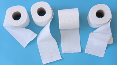 Mavi arka planda beyaz tuvalet kağıdı yuvarlanıyor. Hijyen kavramı.