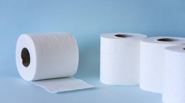 Mavi arka planda beyaz tuvalet kağıdı yuvarlanıyor. Hijyen kavramı.