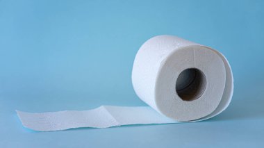 Mavi arka planda beyaz tuvalet kağıdı yuvarlanıyor. Hijyen kavramı.