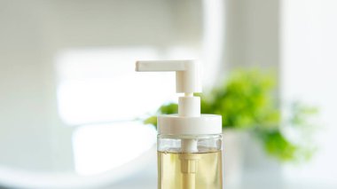 Sıvı sabun şişesi, banyoda sepetin üzerinde gri havlu. Hijyen ve sağlıklı yaşam konsepti. Yaklaş, seçici odaklanma