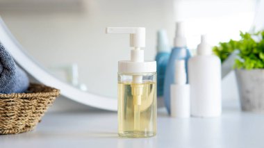 Sıvı sabun şişesi, banyoda sepetin üzerinde gri havlu. Hijyen ve sağlıklı yaşam konsepti. Yaklaş, seçici odaklanma