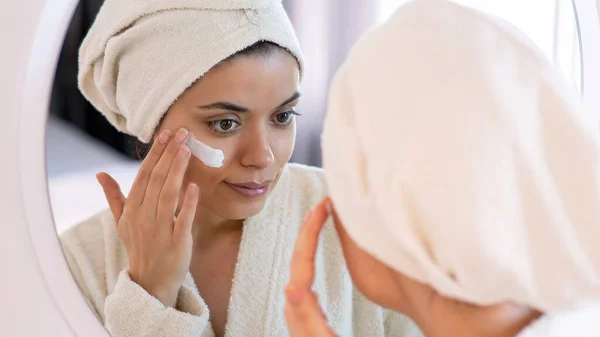 Güzellik, cilt bakımı ve insan konsepti. Cilt bakımında gülümseyen ve ev banyosuna ayna arayan genç bir kadın.