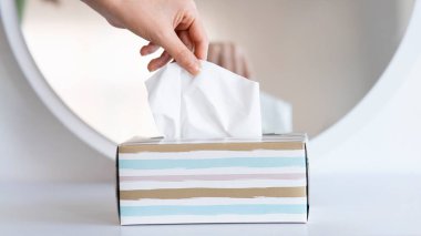 Kadınlar mendil kutusundan peçete kağıdı topluyor.