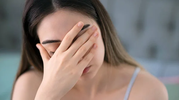 Sad tired young woman touching forehead having headache migraine or depression