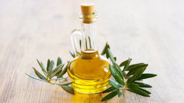 Zeytinyağı ve zeytin meyveleri ahşap masada. 