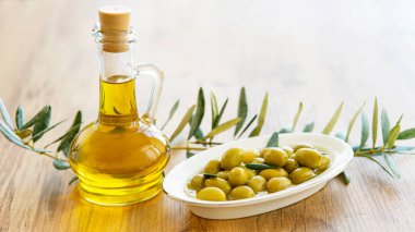 Zeytinyağı ve zeytin meyveleri ahşap masada. 
