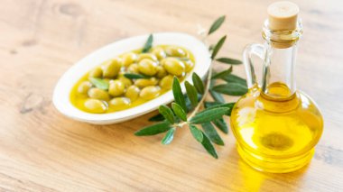 Zeytinyağı ve zeytin meyveleri ahşap masada. 