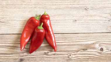 Tahta arka planda izole edilmiş kırmızı biberli olgun meyveler.