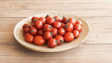 Tahta bir kasede kırmızı kiraz domatesleri. Taze, olgun, küçük ve yuvarlak domatesler..