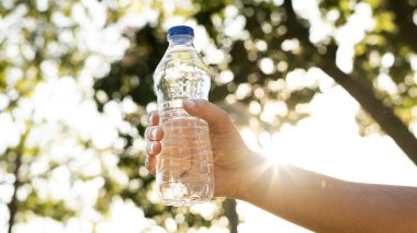 Parkta taze su şişesini tutan el.