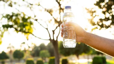 Parkta taze su şişesini tutan el.