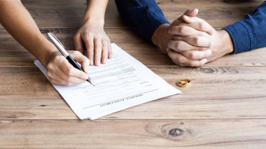İnsan eli boşanma sözleşmesi imzalıyor, yakın plan. Evlilik sözleşmeli nikah yüzükleri ve arka planda Yargıç Tokmak.