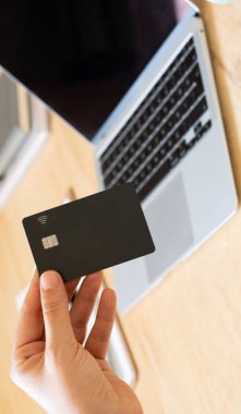 İnternet bankacılığı, evde online alışveriş, klavyede yazı yazan Asyalı genç kadın, kredi kartı tutuyor, dizüstü bilgisayar kullanıyor.