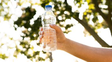 Parkta taze su şişesini tutan el.