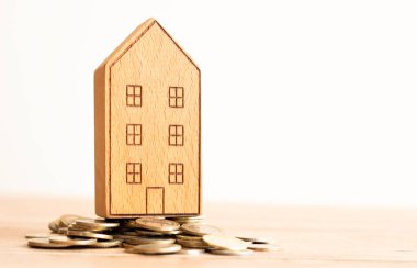 Gayrimenkul kavramı. Ev modeli ve madeni paralar ahşap masaya yığılır, boşluğu kopyala.