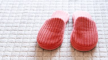 Oturma odasındaki yumuşak beyaz halıda terlikler. Metin için boşluk