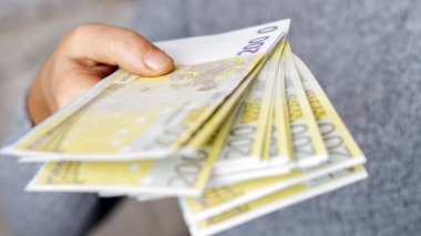 Dolar teklif eden bir kadın, euro banknotları ve bir tomar para tutan bir kadın. Euro, dolar banknotları, Avrupa Birliği kağıt para birimi. Para biriktirme kavramı.