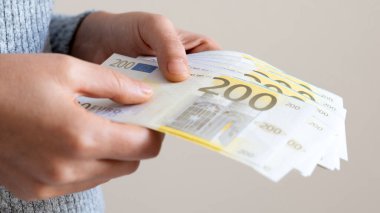Dolar teklif eden bir kadın, euro banknotları ve bir tomar para tutan bir kadın. Euro, dolar banknotları, Avrupa Birliği kağıt para birimi. Para biriktirme kavramı.