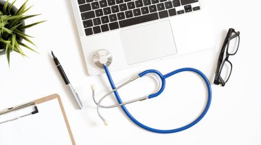 Stetoskop, dizüstü bilgisayar ve metin için kopya alanı olan doktor ofis çalışmalarının üst görünümü.