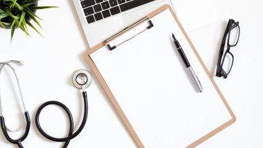 Stetoskop, dizüstü bilgisayar ve metin için kopya alanı olan doktor ofis çalışmalarının üst görünümü.