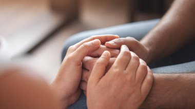 Tanımlanamayan iki insanın el ele tutuşurken yakın plan çekimleri.