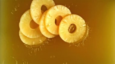 Ananas parçaları ananas suyuna düşer. Film, yavaş çekim 1000 fp. Yüksek kaliteli FullHD görüntüler
