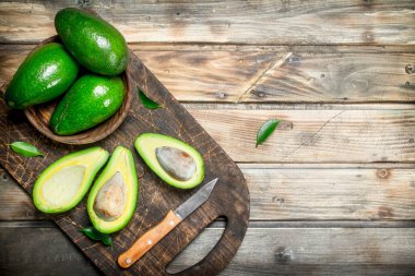 Avokado bir kapta kıyma kurulu bir bıçakla bir siyah. Ahşap bir arka plan üzerinde.