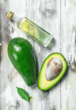 Avokado yağı ve avokado dilimleri. Beyaz ahşap zemin üzerinde.