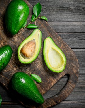 Bir kesme tahtası üzerinde avokado. Siyah bir ahşap arka plan üzerinde.