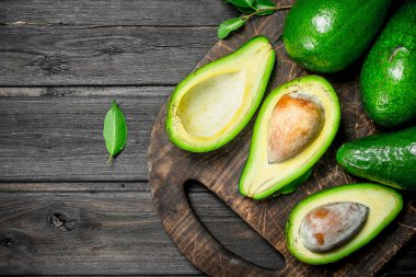 Bir kesme tahtası üzerinde avokado. Siyah bir ahşap arka plan üzerinde.