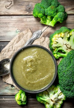 Bir kasede brokoli bir kaşık ile püre. Ahşap bir arka plan üzerinde.