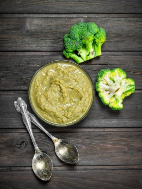 Bir kaşık brokoli püresi. Ahşap bir arka plan üzerinde.
