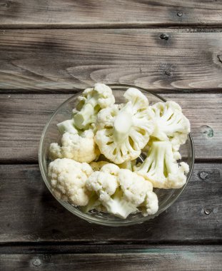 Karnabahar bir cam kabın içinde. Ahşap bir arka plan üzerinde.