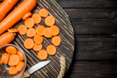 Bir bıçak ile kesme tahtası üzerinde taze havuç. Ahşap arka plan üzerinde