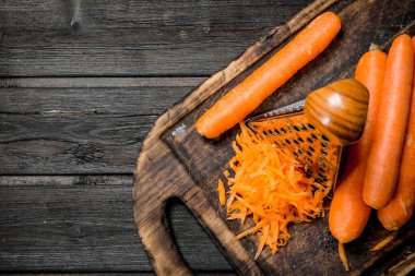 Rendelenmiş havuç rende ile bir kesme tahtası üzerinde. Ahşap arka plan üzerinde