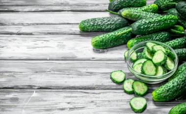 Bütün salatalık ve salatalık dilimleri kabın içinde. Ahşap arka plan üzerinde