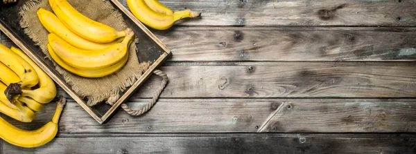 Fresh bananas on the bag in the old dressing. On a black wooden background.