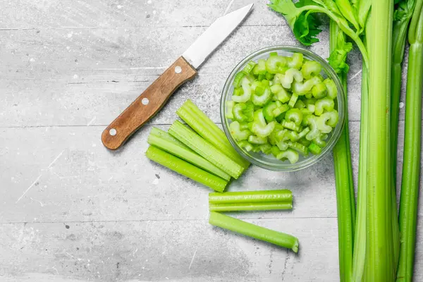 Kereviz bir bıçak ile bir kase dilimlenmiş. Rustik arka plan üzerinde