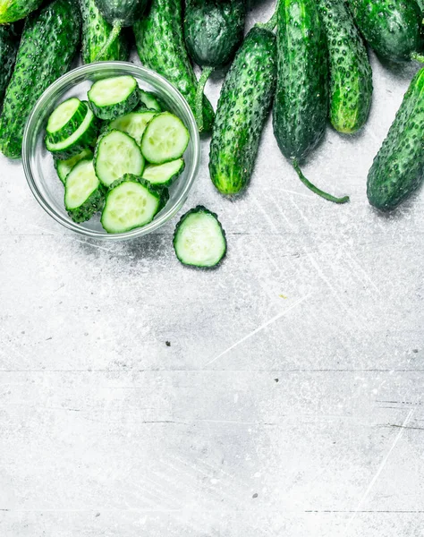 stock image Cucumbers and pieces of fresh cucumbers in the bowl. On rustic background