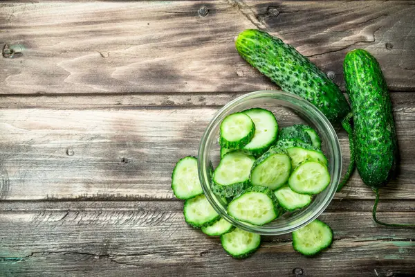 Stock image Pieces of fresh cucumbers in the bowl. On wooden background