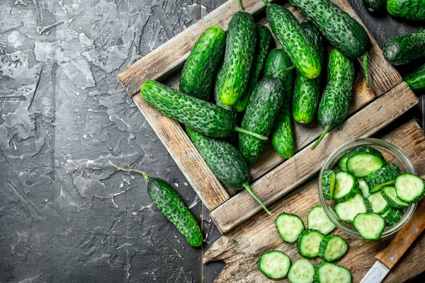 Salatalık tepsi ve salatalık dilimleri bir bıçak ile kesme tahtası üzerinde. Rustik arka plan üzerinde