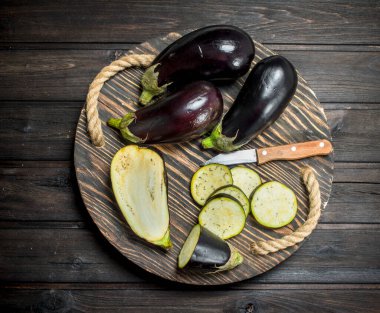 Patlıcan bir bıçak ile kesme tahtası üzerinde parçaları. Ahşap arka plan üzerinde