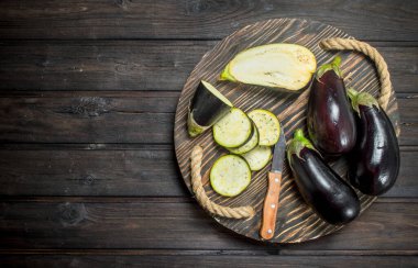 Patlıcan bir bıçak ile kesme tahtası üzerinde parçaları. Ahşap arka plan üzerinde