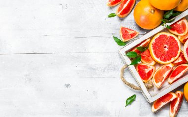 Bir tepsi üzerinde olgunlaşmış greyfurt parçaları. Beyaz rustik arka plan üzerinde