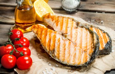 Domates ve limon ile ızgara somon. Ahşap bir arka plan üzerinde.