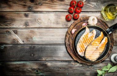 Baharat ve otlar ile bir tavada kızarmış som balığı. Ahşap bir arka plan üzerinde.