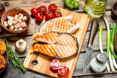 Somon ızgara biftek çeşitli sebze ve baharatlar ile. Ahşap bir arka plan üzerinde.