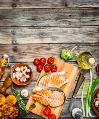 Somon ızgara biftek çeşitli sebze ve baharatlar ile. Ahşap bir arka plan üzerinde.